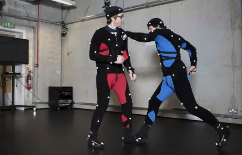 two boys with motion capture suits on one with red suit and the other with blue suit, the one with a blue suit punching the guy with the red suit on the right shoulder